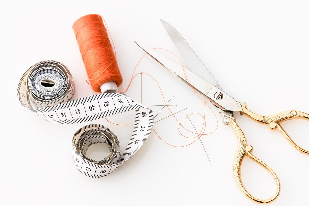 Soft tailor's measuring tape with thread and scissors, used to measure lingerie size at home